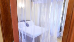 A room with a bed covered by a sheer white canopy.
