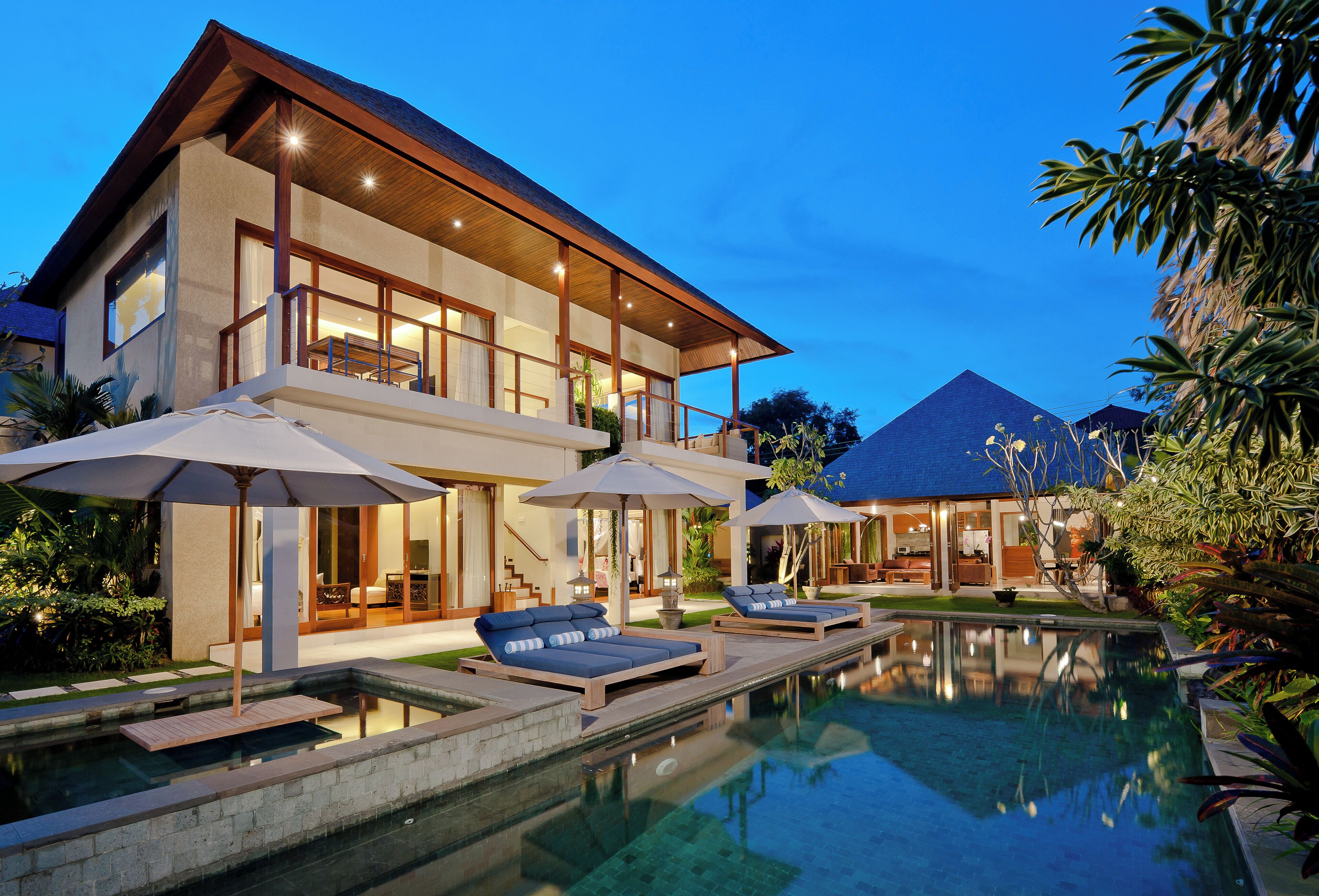 A modern house with a swimming pool, outdoor seating, and large windows.