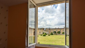 A room with a large window overlooking a historic building and a well-maintained lawn. - Charming Cottage with Historic Castle Views, 7 Hectares, Bikes, Near Cognac (Cherves-Richemont)