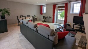 A modern living room with a sofa, dining table, chairs, and a TV. - Charming Cottage with Historic Castle Views, 7 Hectares, Bikes, Near Cognac (Cherves-Richemont)