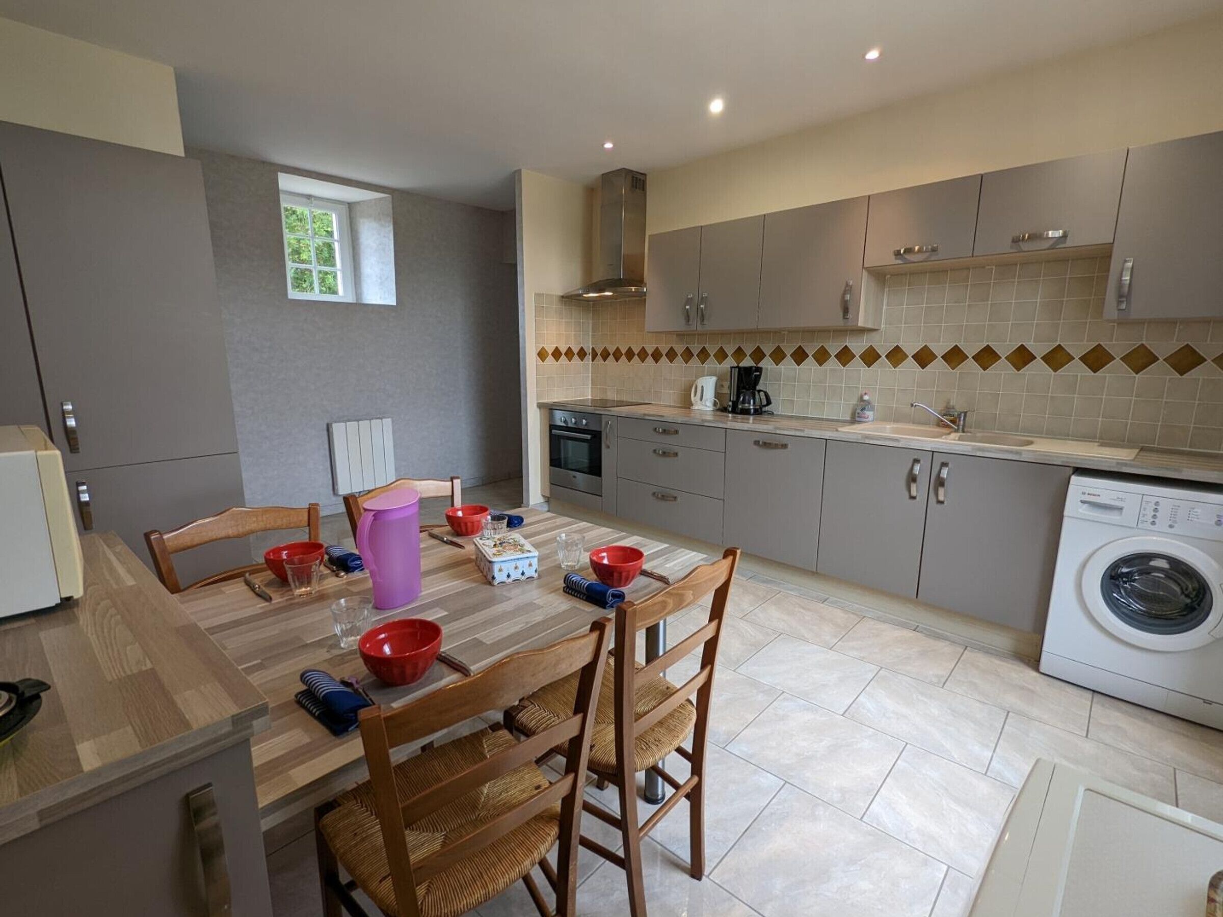 A compact kitchen with a dining table, chairs, and a washing machine.