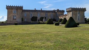 A large, historic stone building with symmetrical architecture, featuring multiple towers and a well-maintained lawn with trimmed hedges. - Charming Cottage with Historic Castle Views, 7 Hectares, Bikes, Near Cognac (Cherves-Richemont)
