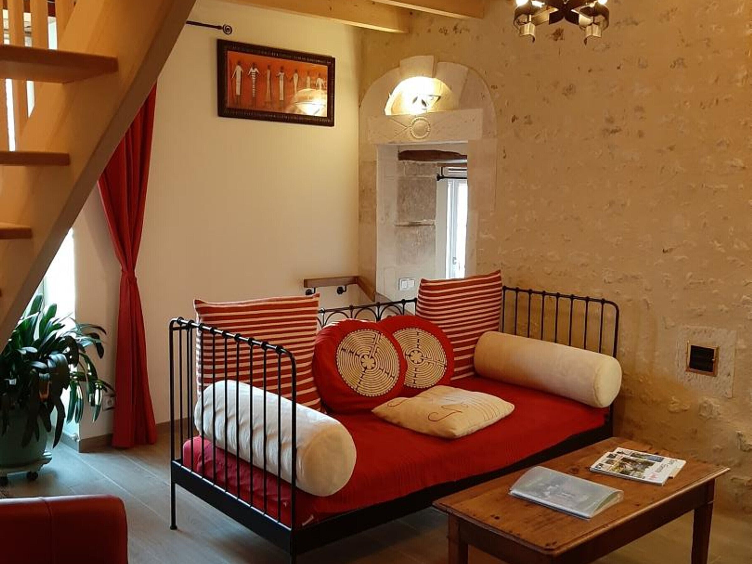 A cozy living room with a red sofa, a wooden coffee table, and a staircase.