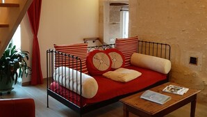 Un salón acogedor con un sofá rojo, una mesa de centro de madera y una escalera.
