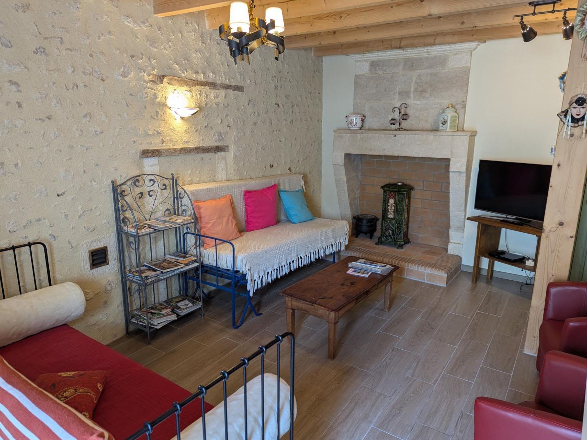 Una sala de estar acogedora con chimenea de piedra, un sofá, una mesa de centro y un televisor.