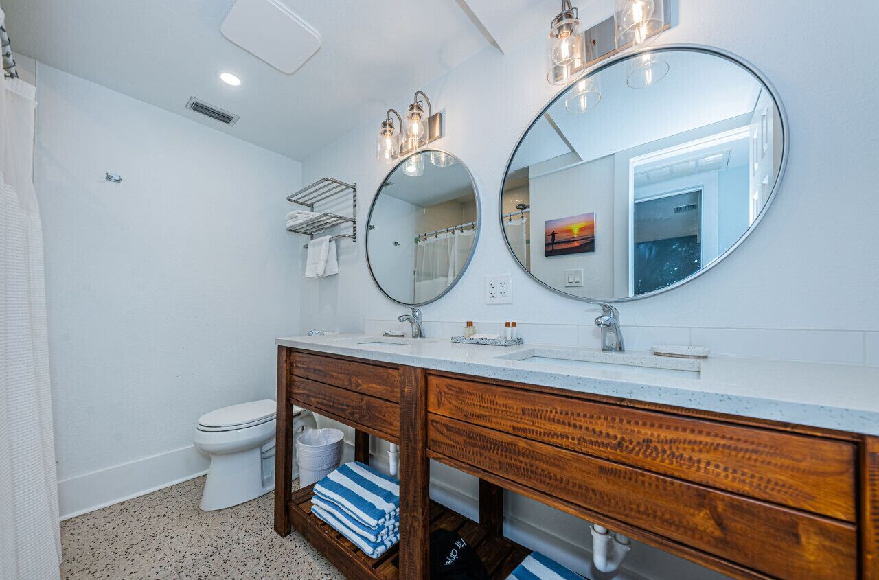 A bathroom with a white toilet, a wooden vanity with a mirror, and a towel rack.