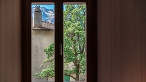 Une fenêtre donnant sur un bâtiment avec une cheminée et un arbre.