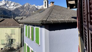 Un bâtiment doté d’un toit en pente et de volets verts, se dressant sur fond de montagnes enneigées.