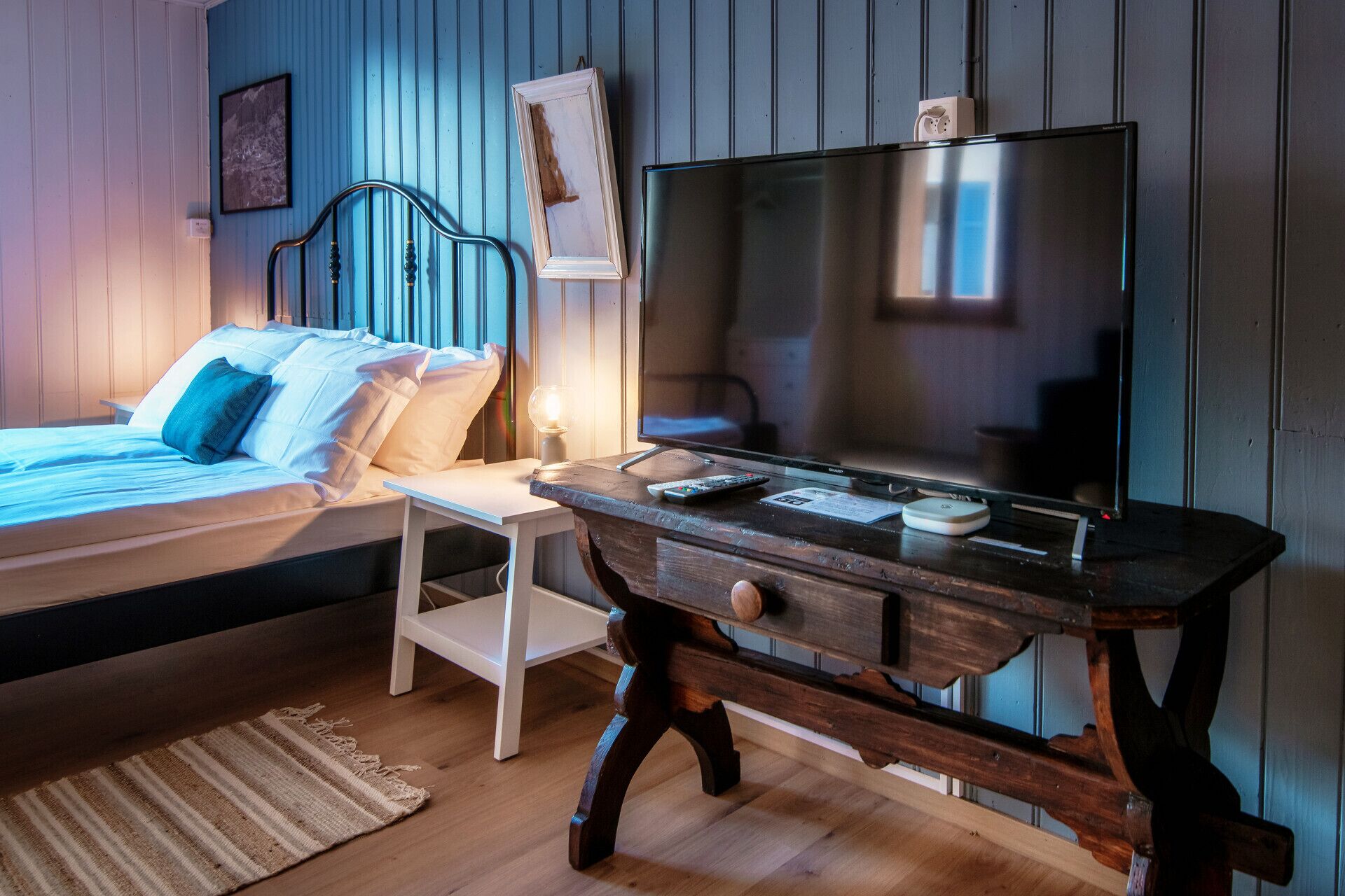 Une chambre à coucher avec un lit, une table de chevet, une télévision et des murs en bois.