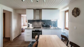 Une cuisine moderne avec des meubles blancs, un plan de travail noir et une table à manger en bois.