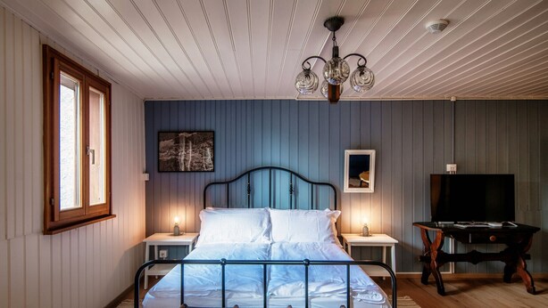 Une chambre à coucher avec un lit, des tables de chevet, une télévision et un lustre.
