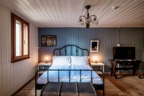 A bedroom with a bed, bedside tables, a television, and a chandelier. - Lovely one-bedroom apartment in typical mountain house (CHIÈRA) (Osco)