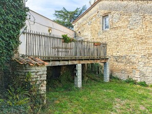 A stone building with a wooden balcony supported by columns. - Charming stone cottage with stove, pets allowed (Asnières-sur-Nouère)