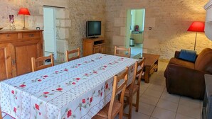 Une pièce chaleureuse avec une table à manger, des chaises en bois, un téléviseur et un canapé.