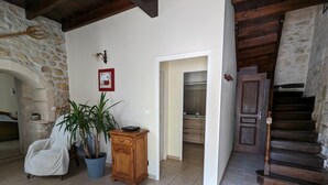 A spacious living area with a stone wall, a wooden staircase, and a view into a kitchen. - Renovated house near Angoulême with private garden (Vindelle)