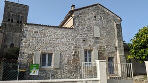 A stone building with a bell tower, a gated entrance, and a sign indicating it is a Gîte. - Renovated house near Angoulême with private garden (Vindelle)