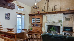 A cozy living room with a fireplace, wooden furniture, and a television. - Charming stone cottage in Bellon with garden, fireplace and internet (Bellon)