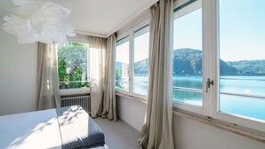 Une chambre avec une grande fenêtre donnant sur un lac et des collines.