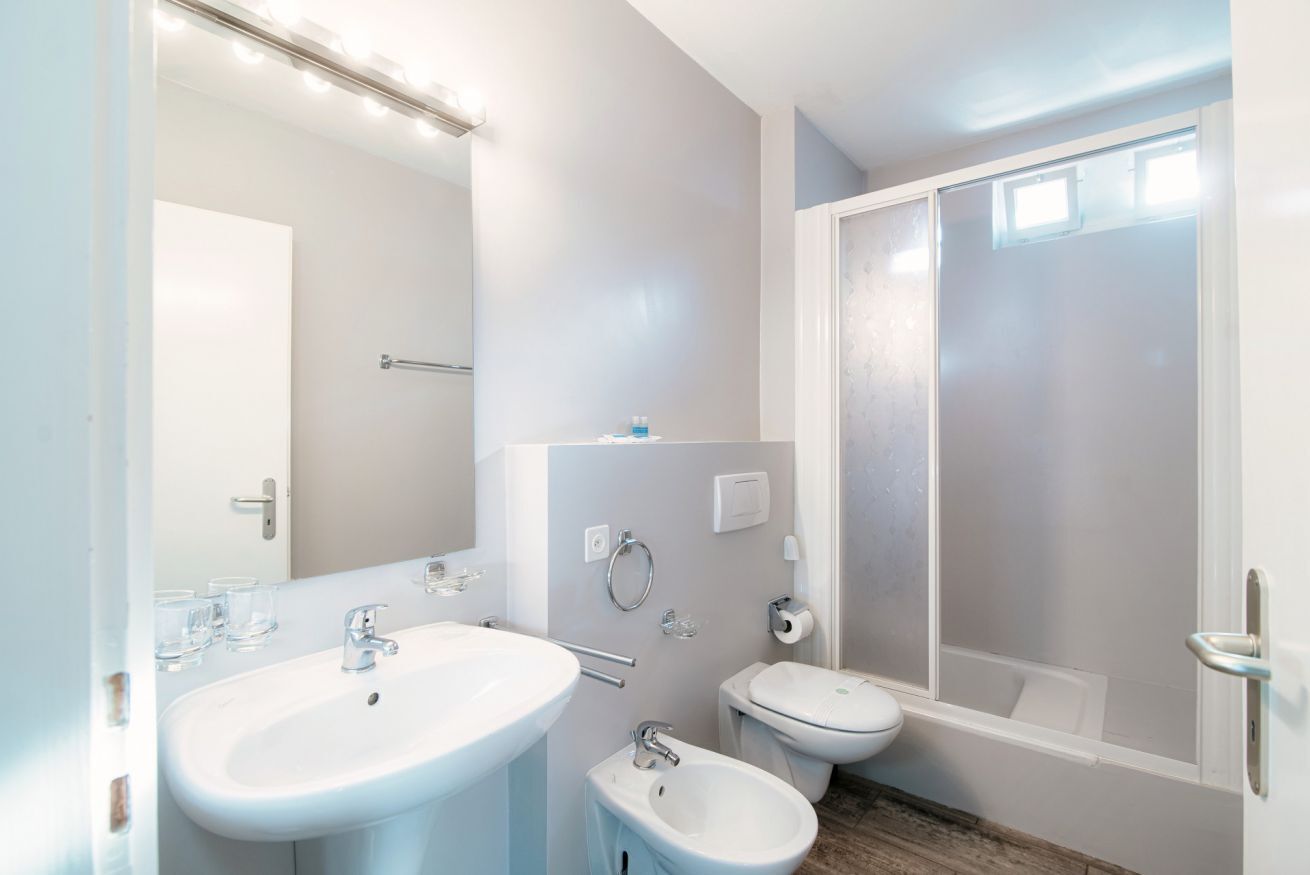 A modern bathroom with a sink, bidet, toilet, and shower.