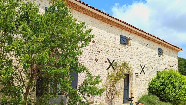 A stone building with a tiled roof, a bicycle parked outside, and a gravel path leading to the entrance. - Spacious Stone House with Shared Pool, Babyfoot, and Nature Trails in Bucolic Setting (Montmoreau)