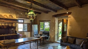Une cuisine rustique avec des poutres en bois, un lustre et un coin repas comprenant un canapé et une table basse.