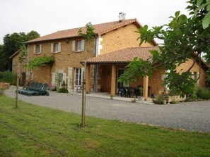 A two-story house with a tiled roof, a gravel driveway, and outdoor seating. - La Queue Rousse Cottage - Historic Home with Fireplace and Enclosed Garden (Vitrac-Saint-Vincent)