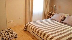 A bedroom with a striped bedspread, a bedside lamp, and a wooden nightstand.