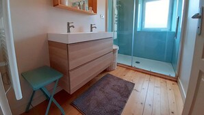 A bathroom with a wooden vanity, two sinks, a mirror, and a glass shower enclosure.