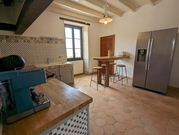 A kitchen with a wooden countertop, a built-in stove, a refrigerator, and a window with a view. - Charming Cottage with Heated Pool, Terrace, and Enclosed Garden in Aubeville (Val des Vignes)
