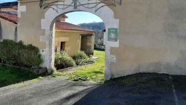 A building with a tiled roof, an archway, and a sign indicating a Gite. - Family cottage in village, pets allowed (Salles-Lavalette)
