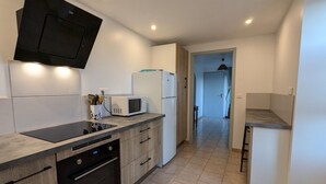 A modern kitchen with a built-in microwave, oven, and a black range hood. - Family cottage in village, pets allowed (Salles-Lavalette)
