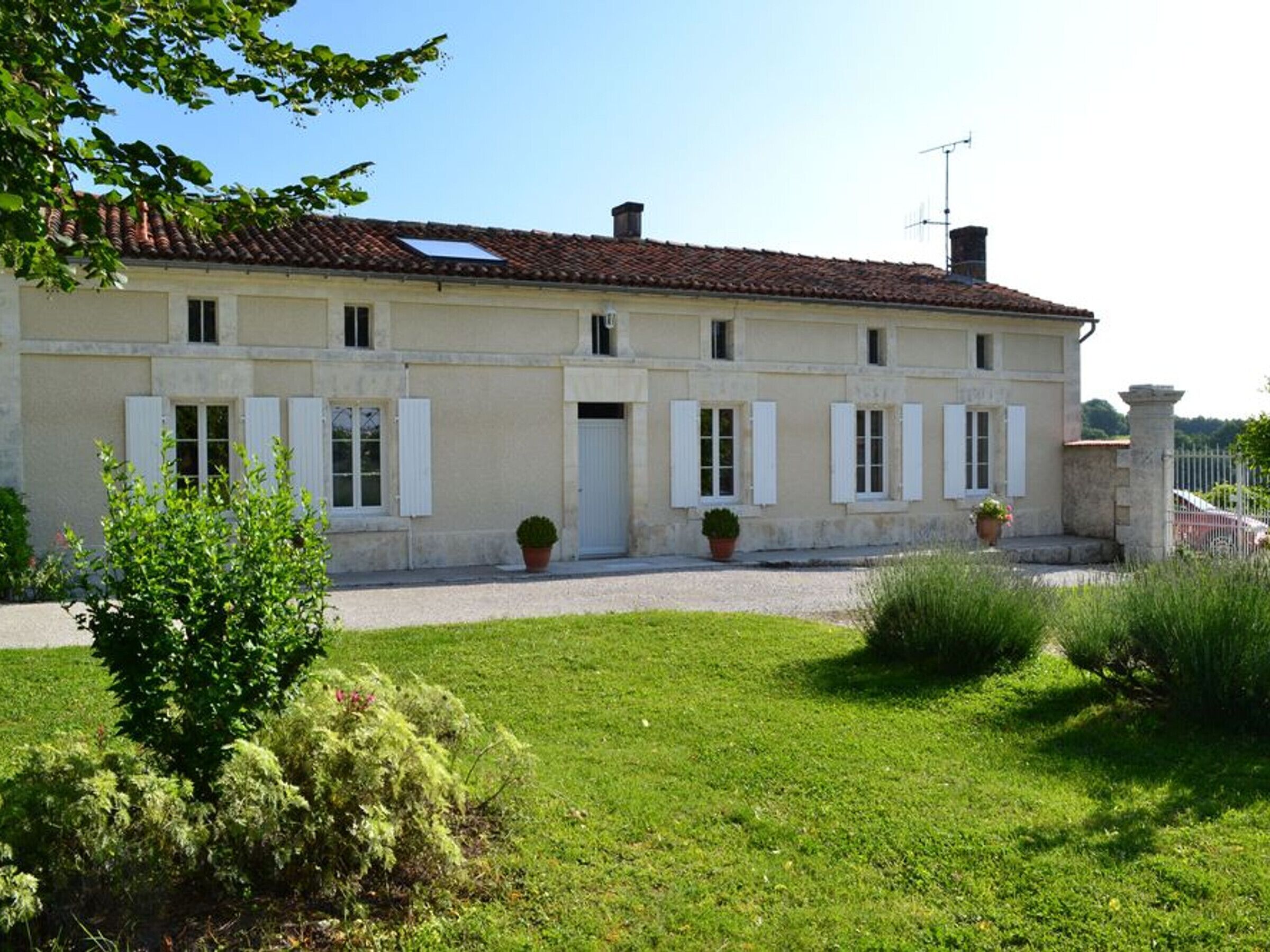 Un bâtiment à deux étages, doté d’un toit recouvert de tuiles, de volets blancs et d’une allée gravillonnée.