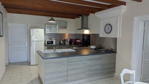 Una cocina moderna con una isla central, armarios blancos y techo de madera.