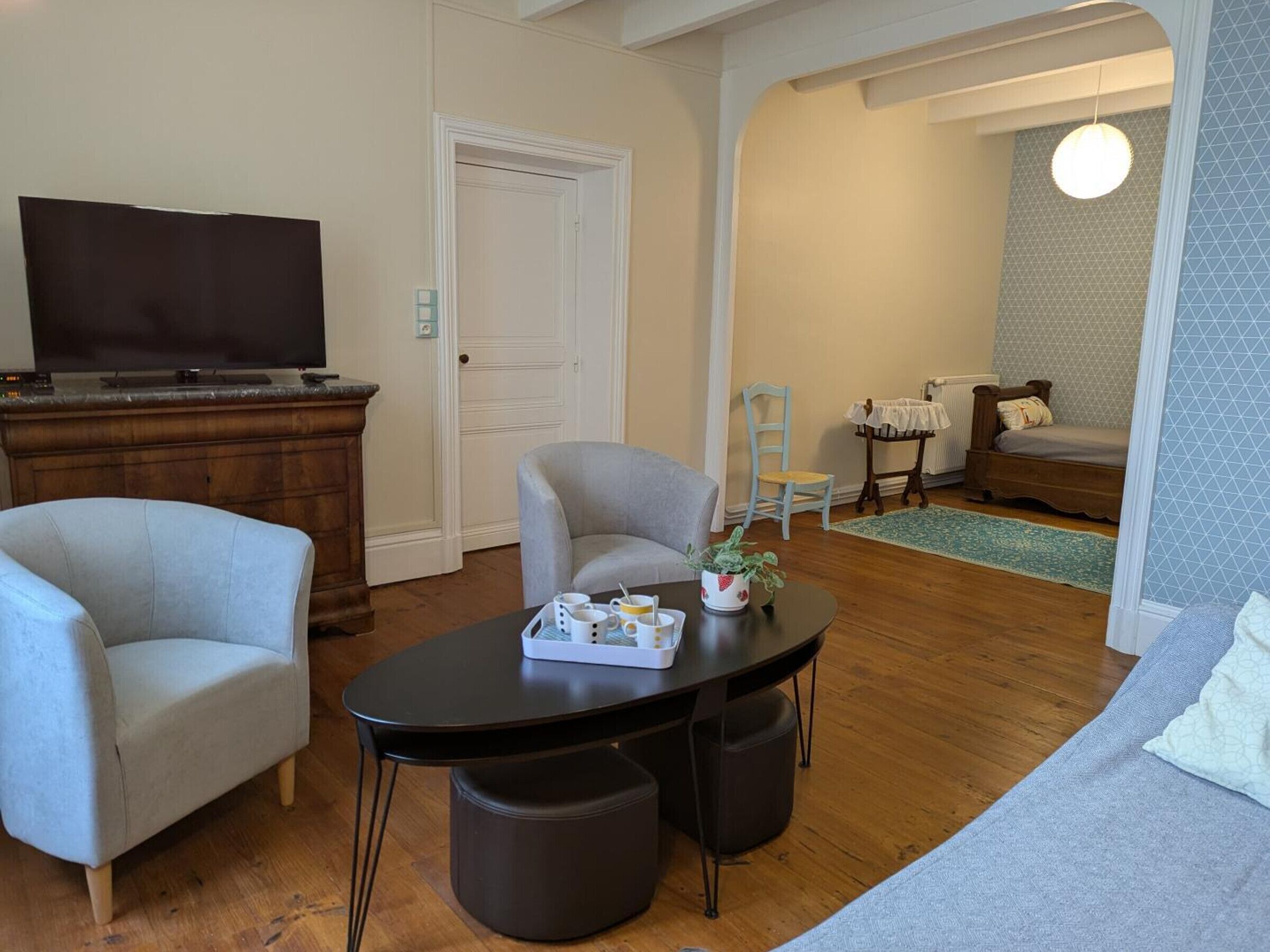 A living room with a television, two armchairs, a coffee table, and a small table with a plant.