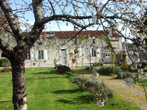 A building with a tiled roof, surrounded by a well-maintained lawn and flowering trees.