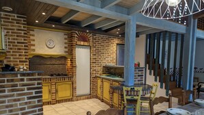 A rustic kitchen with exposed brick walls, wooden beams, and a built-in stove. - Charming Cottage with Heated Pool and Private Garden in Charras, Near Périgord (Charras)