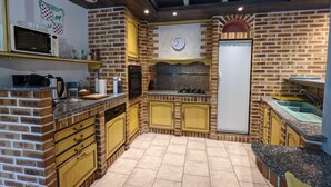 A kitchen with brick walls, yellow cabinets, a microwave, a stove, and a refrigerator. - Charming Cottage with Heated Pool and Private Garden in Charras, Near Périgord (Charras)