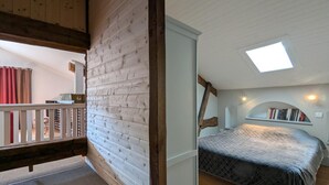 A bedroom with a sloped ceiling, a skylight, a bed, a bookshelf, and a view of a balcony. - Charming Cottage with Heated Pool and Private Garden in Charras, Near Périgord (Charras)