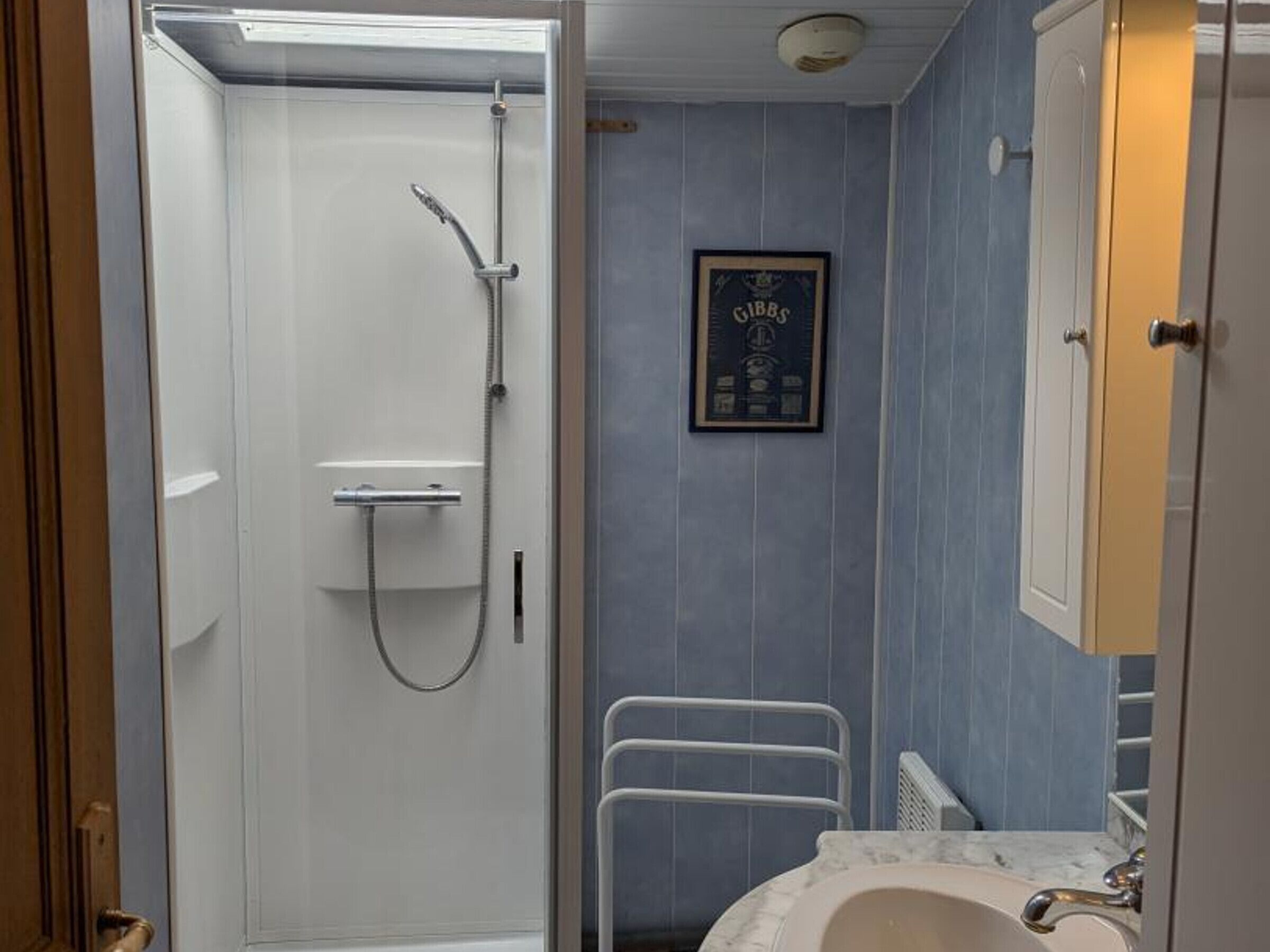 Un bagno con doccia, lavandino e un certificato incorniciato appeso al muro.