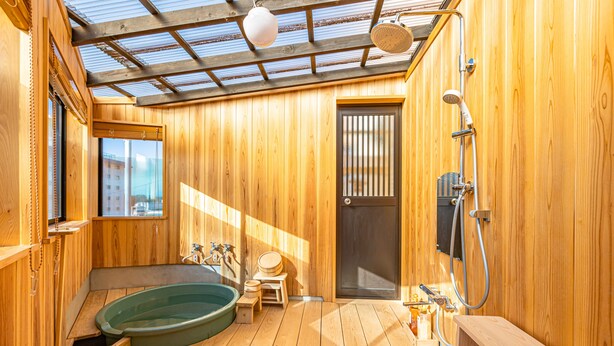 Une salle de spa en bois équipée d’un bain à remous, d’une douche et d’un petit banc en bois.