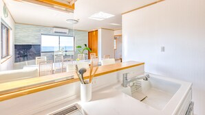 Une cuisine moderne dotée d’un grand îlot central, d’un four encastré et offrant une vue sur l’océan.