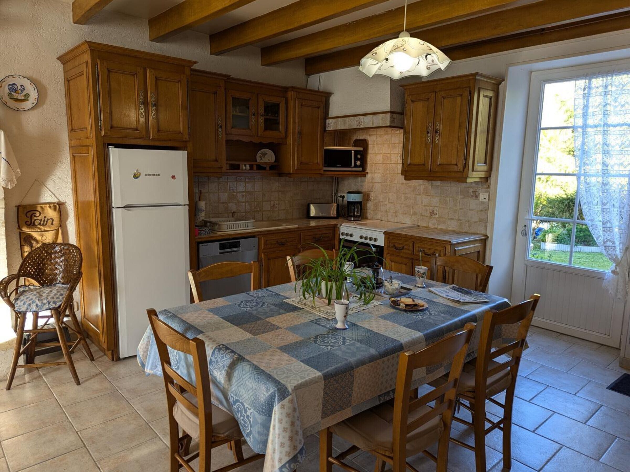 Une cuisine avec des meubles de rangement en bois, un réfrigérateur, une cuisinière et une table à manger avec des chaises.
