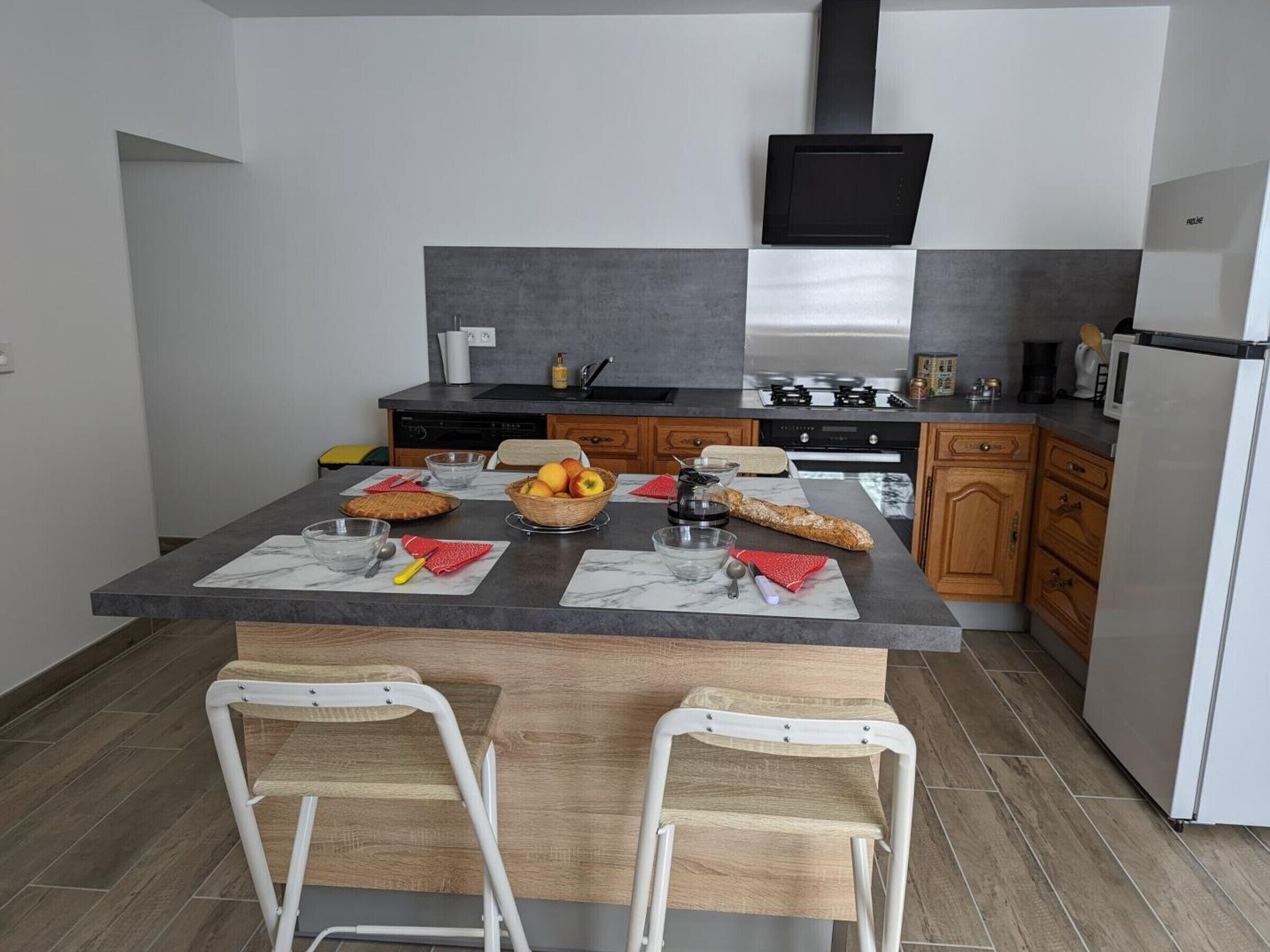 Une cuisine moderne dotée d’un îlot central, de meubles en bois, d’un four encastré et d’un téléviseur à écran plat.