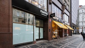 A building with a 'numa' storefront, a 'Poise' sign, and a 'Boulangerie' with a yellow awning. - Numa Prague Poise (Prague)