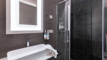 A modern bathroom with a freestanding bathtub, a glass-enclosed shower, and a wall-mounted mirror.