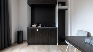 A modern room with a dark wood cabinet, a small table with two glasses, and a white chair. - Numa Prague Poise (Prague)