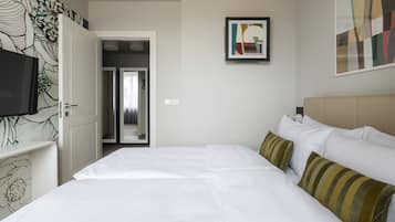 Een hotelkamer met een groot bed, een televisie en een deur naar een gang.