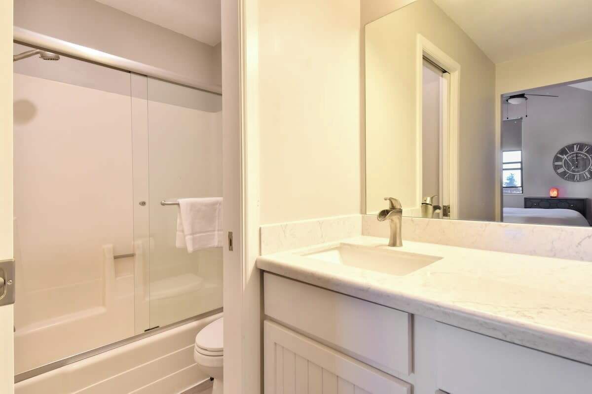 A modern bathroom with a glass-enclosed shower, a white sink, and a large mirror.