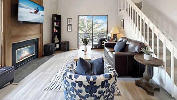 A spacious living room with a fireplace, a large flat-screen TV, a ceiling fan, and a staircase leading to an upper level. - Canyons Resort - Walking Distance Sunrise Gondola! (Park City)