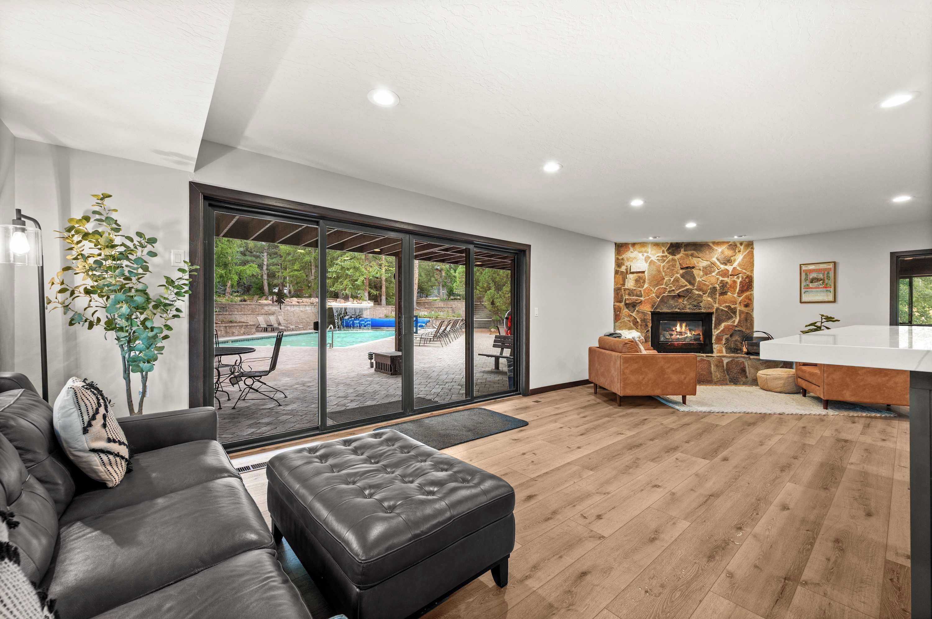 A modern living room with a fireplace, a pool view, and a cozy seating area.
